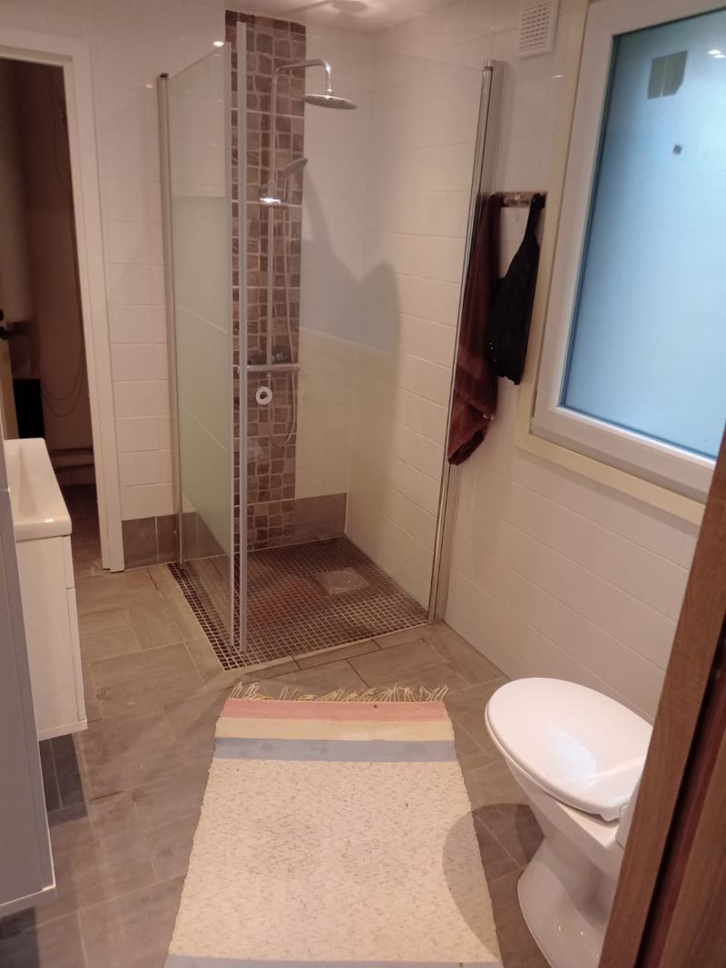 Duschrum med duschväggar i glas, mosaikbård och klinkergolv