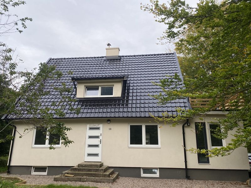 Villa med nytt svart tak och takkupa, putsad ljus fasad och nya fönster