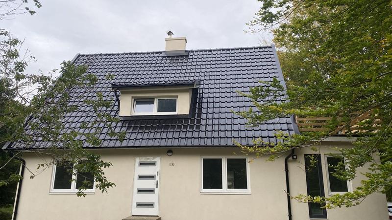 Villa med nytt svart tak och takkupa, putsad ljus fasad och nya fönster